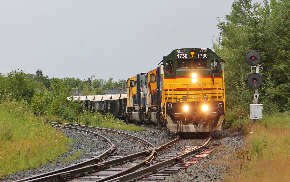 After arriving in Rouyn-Noranda, QC in a downpour, ONT 211 shoves its train of empty acid tanks and loaded copper slurry gons over the diamond with CN's Val-d'Or Subdivision. We believe these are the last operational ONR searchlights left.
