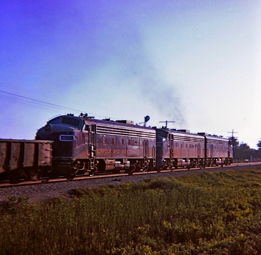 Early evening grab shot, a Kodak Instamatic Moment of N&W train #91 flying along westward into the sunset after having clattered over the diamond of the CN Dunnville sub. Notes from the day indicate the train had 58 cars and went by at 19:40 on a beautiful summer evening.