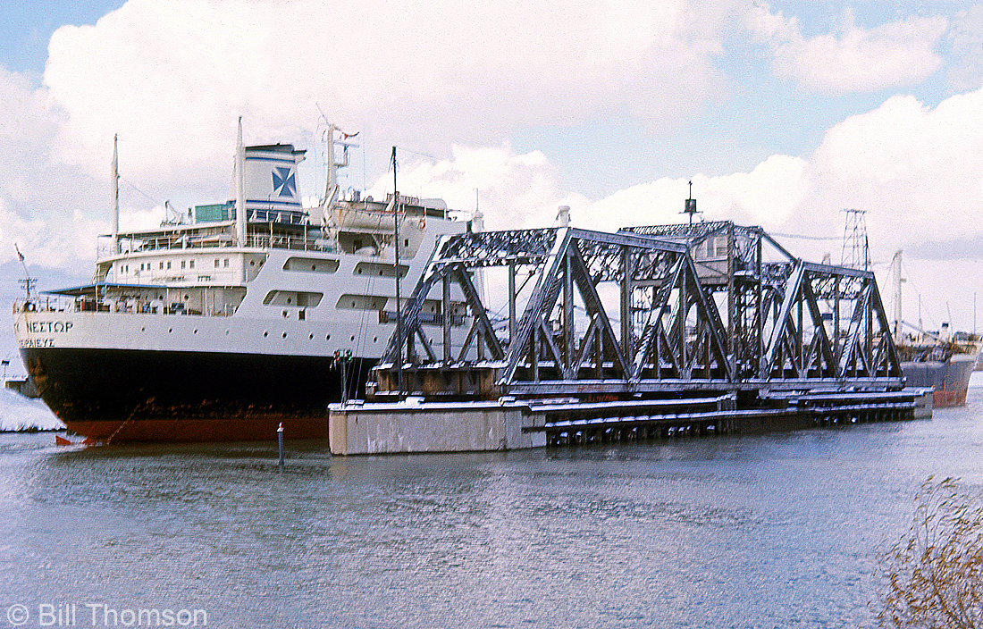 The bridge tender has moved the swing bridge carrying Penn Central's Canada Division line (the CASO) into the open position to let a ship pass through the Welland Canal during December 1969, resulting in a brief pause in rail traffic. Increasing levels of ship traffic through the canal was one of the reasons that lead to the new canal alignment and construction of the Townline Tunnel, which opened a few years later and ran underneath the canal, eliminating the interruptions in mainline railway traffic for marine traffic.