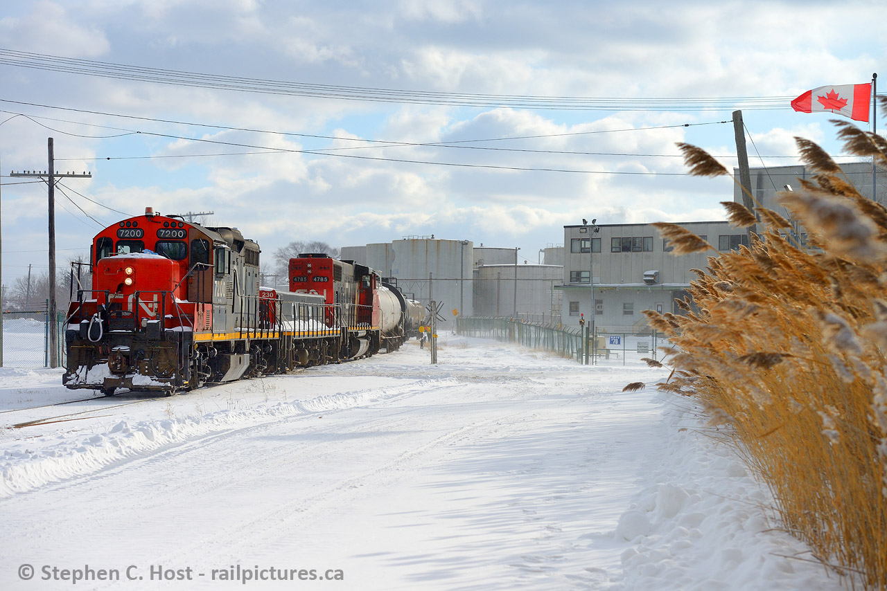 Yeeeesh who would go out in this weather? This looks friggin' cold. But at least the Canada flag is sticking out. So is frostbite if you stood out in this for too long. However, I'm standing on Divine St just a couple blocks from my in-laws house, I heard the horns and went out to investigate, the IOX job is busy drilling Imperial Oil. What's sad about this photo is the tank farm in the background, full of nice old riveted 19th century oil infrastructure is now all gone and demolished. Just about everything here is gone EXCEPT the railway and the Imperial loading racks , which still get rail service, actually. So the stuff we tend to care about is present.  For anyone  who may ever find themselves here, just to the right crossing Divine St from the yard is a spur that goes off toward the water - this is the CNR/CSX north interchange, end of CSX track, although not marked, is visible to you when standing here (Mile 71.x Sarnia sub).