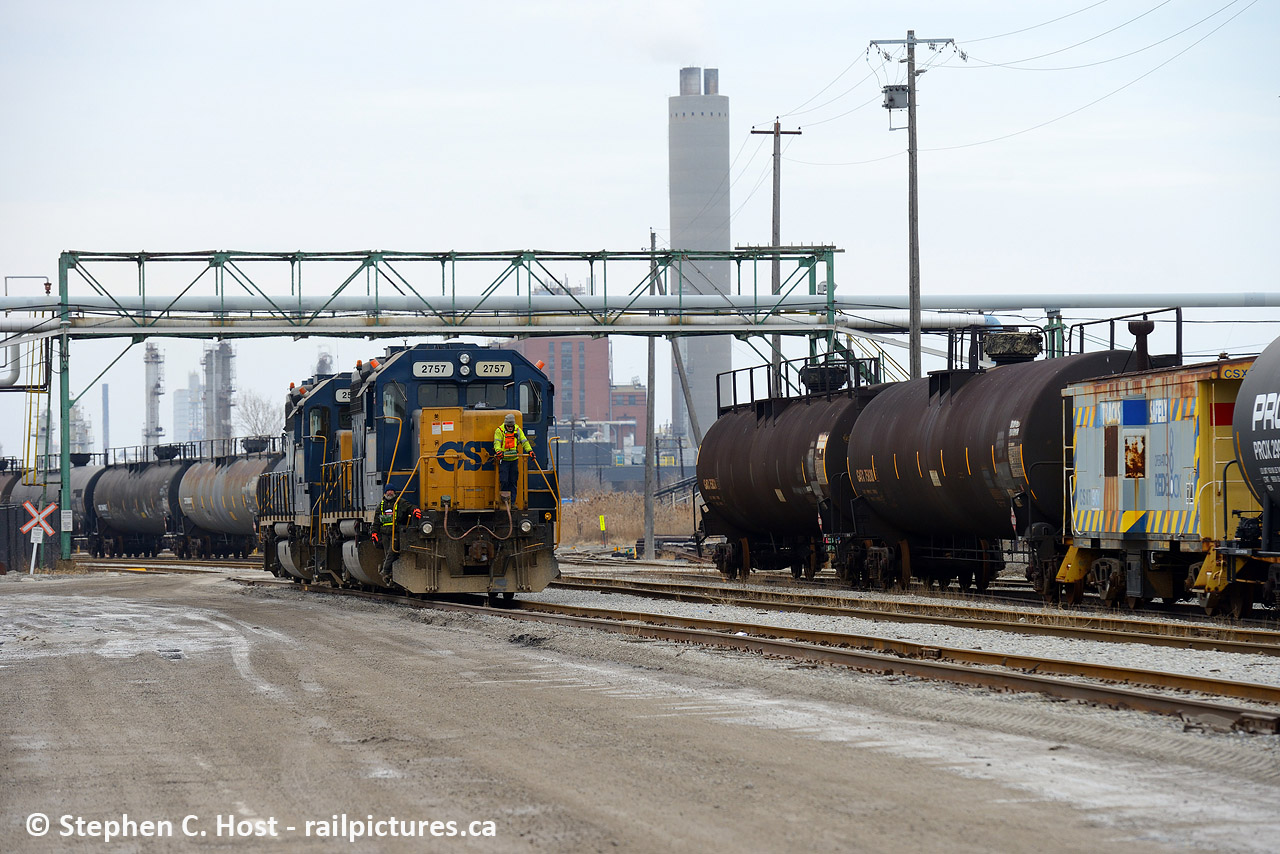 Deep in the heart of the industrial area of Sarnia, the weekend yard job is returning north to home base after finishing work for the day, passing under the usual gaggle of industrial overhead pipelines. At right in a cut of cars is the Operation RedBlock caboose (900074), one of two (900032 in Chessie paint being the other) that were assigned to Sarnia for a couple decades used for any jobs that have long reversing moves. Within a year these two would be collected by the station and sold to the Lake State Railway who have them now and IIRC have since repainted them. Amazing that CSX hangs on to this isolated patch after all this time.