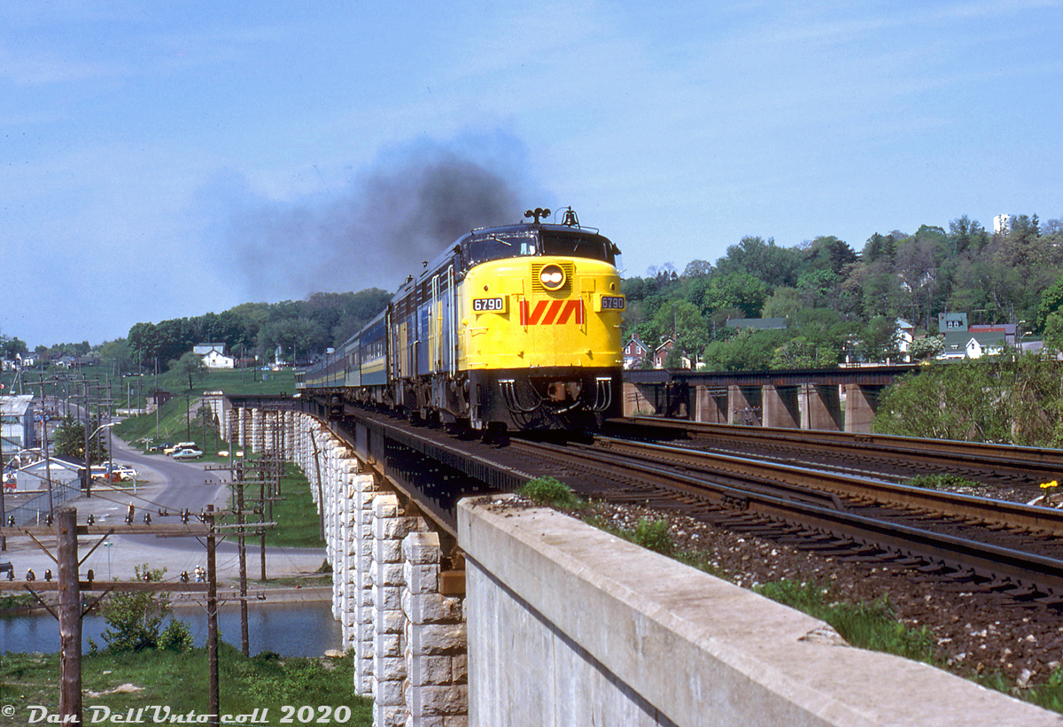 VIA 6790 and a sister FPA4 thunder over the Port Hope viaduct, handling a sizable VIA train from Toronto eastbound over the Kingston Sub. The viaduct around Mile 270 of CN's Kingston Sub was built by CN predecessor Grand Trunk in the 1850's to spans the Ganaraska River and harbour area. One can see two sets of crossbucks along Hayward Street below for the industrial spurs accessing the harbourfront industries to the south (including the Eldorado Nuclear Limited uranium conversion facility, that had sidings off the harbourfront and to the west). CP's Belleville Sub crosses over the adjacent viaduct in the background.

Dennis Nehrenz photo, Dan Dell'Unto collection slide.