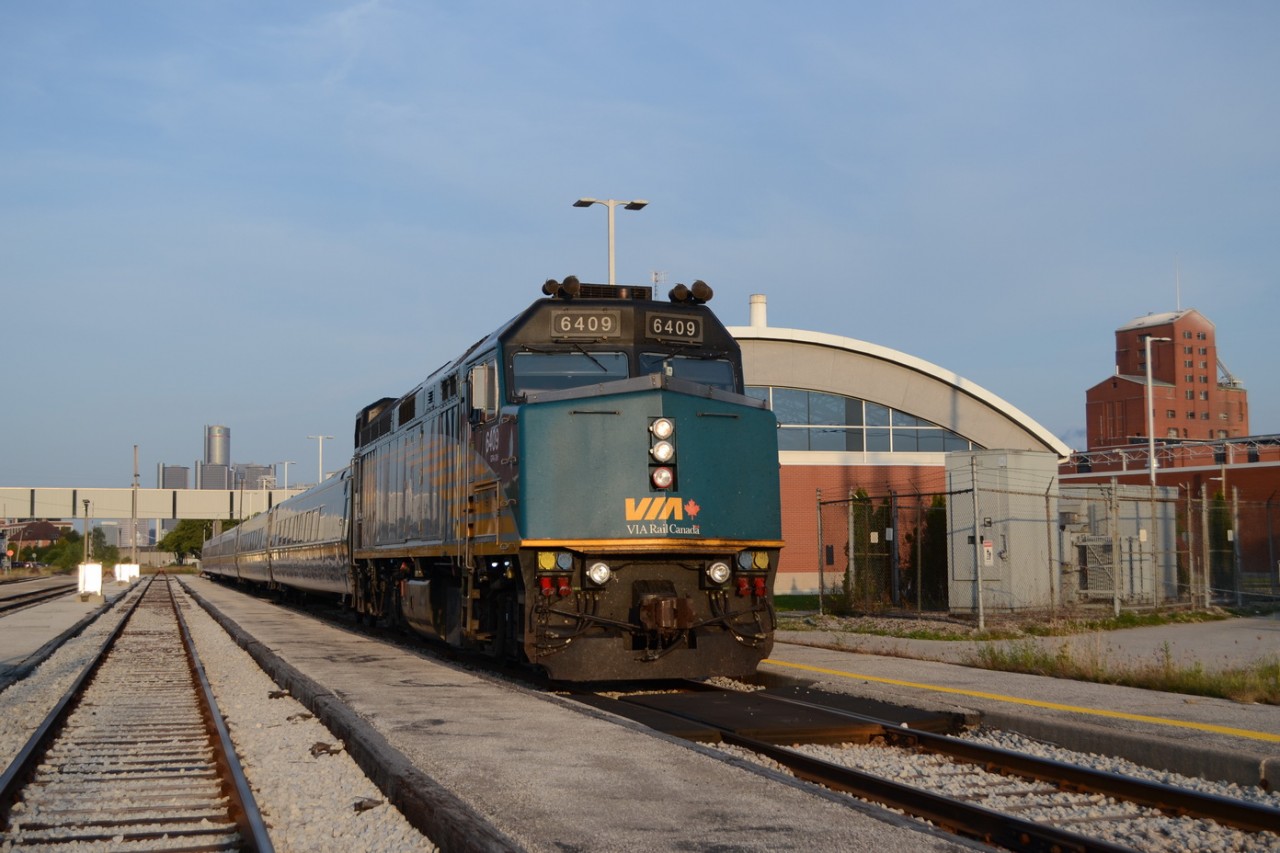 VIA 6409 sits under early morning light, with the Iconic GM Renaissance Center on the left from Detroit, Michagan, across the Detroit River, and on the right side Hiram Walkers factory, from the mid 1800s. Both Major staples of the region. A warm welcome sight to people coming to Windsor, and leaving the town.