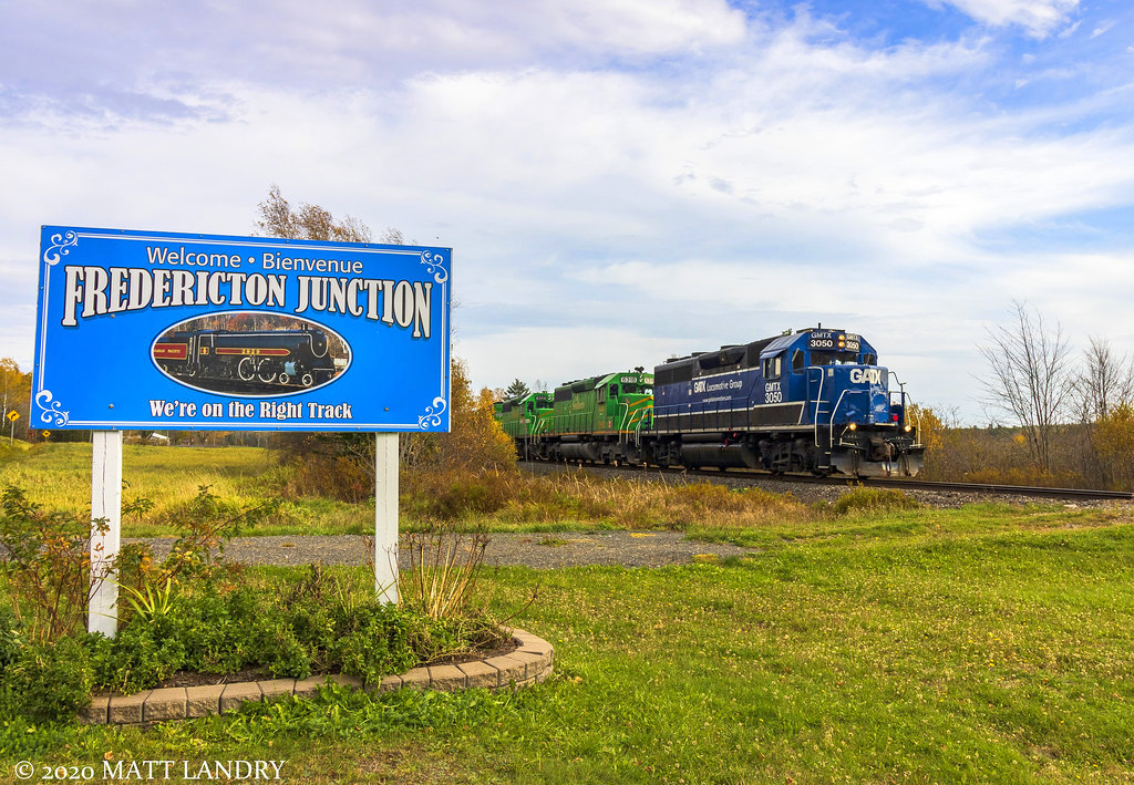 NBSR train 907 is westbound, heading out of Fredericton Jct, New Brunswick, passing the village sign.