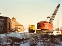 A bitterly cold mid-February morning see 1949 built GE 50 Ton Center Cab (likely #4 but unnumbered from 1977 onward) in safety yellow (formerly painted in steel plant red) resting next to 1957 built American Magnetic Rail Crane on the Canadian Furnace Division property of Algoma Steel Corporation.  Starting in January 1981 the pair were put to work regularly to load gondolas with the mountains of pig iron that lined the north side of the property for the past 4 years since the Blast Furnace was idled.  With dismantling of the plant to start in the summer of 1981, the task of cleaning up the inventory and moving out the in-house fleet of rolling stock was job #1.  The American Rail Crane was transferred to Algoma Steel in Sault Ste. Marie later that same year as their #5 Rail Crane (2nd), eventually moving to the ACR as their 10216 (2nd), Wisconsin Central as 9404 and finally CN as their 9404.  It is still active on the CN roster.  It appears that the #4 Locomotive is at the Colorado Railway Museum since 2004, so it also survived.  The view is looking north, the Company Engine house is on the left, and Welland Canal Lift Bridges in the distance. Special thanks to Paul O'Shell for providing the Rail Crane background and the whereabouts of Canadian Furnace #4 GE 50 Ton.      