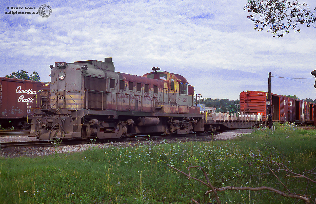 CPR RS3 8459 rests at Orangeville with a cut of cars on a summer day. Built by MLW in 1954, this locomotive would serve it's entire career in the tattered script scheme, retired on October 3, 1979, and scrapped at Angus Shops.Arnold Mooney shot 8459 around Woodstock in June, 1979, just months before retirement:Departing the "shop track" at Woodstock: June 12, 1979.Northbound near Mount Elgin, returning from Tilsonburg: June 12, 1979.Working the west end of Woodstock: June 16, 1979.