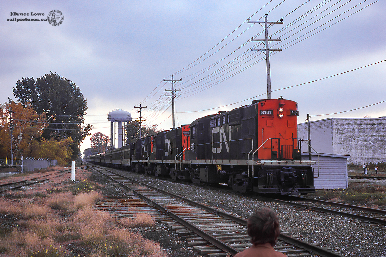A cold and damp Thanksgiving weekend 1974 finds a trio of freshly painted MLW RS18s lugging a 15 car passenger extra along the rails of the Meaford subdivision bound for the line's namesake town about 20 miles away.  The extra, organized by Eric Winkler, M.P.P. for Grey South, was run from Toronto's Union Station to the annual Meaford Applefest.  Bringing up the rear of the consist was the Upper Canada Railway Society's observation car #13, and CN business car #94, assigned to the Vice-President of the Great Lakes Region of Canadian National, Mr. K. Hunt. 
 According to the UCRS November/December, 1974 newsletter, the train would be followed from Allandale to Meaford by a pair of GP9s; 4511, 4503, to switch out the consist for the return trip, as well as to help the heavy train up the hill out of town.  The plan was to cut off the geeps at Allandale, but as no RS18s were facing south, the geeps were kept on the lead; five first generation units hauling 15 cars back to Toronto.  Consist is noted as the following:  Power 3101, 3103, 3118, steam generator 15478, coaches 5413, 5285, 5228, 5423, cafe lounge 752, coaches 5203, 5185, 5214, cafe lounge 753, coaches 5285, 5183, 5210, U.C.R.S. 13, CN 94.This would be the second large passenger consist to pass through Collingwood in 1974, as on June 15, the 17-car "Journey to History" excursion was run to celebrate the christening of the new ferry, "Chi-Cheemaun", and Meaford's centenary.