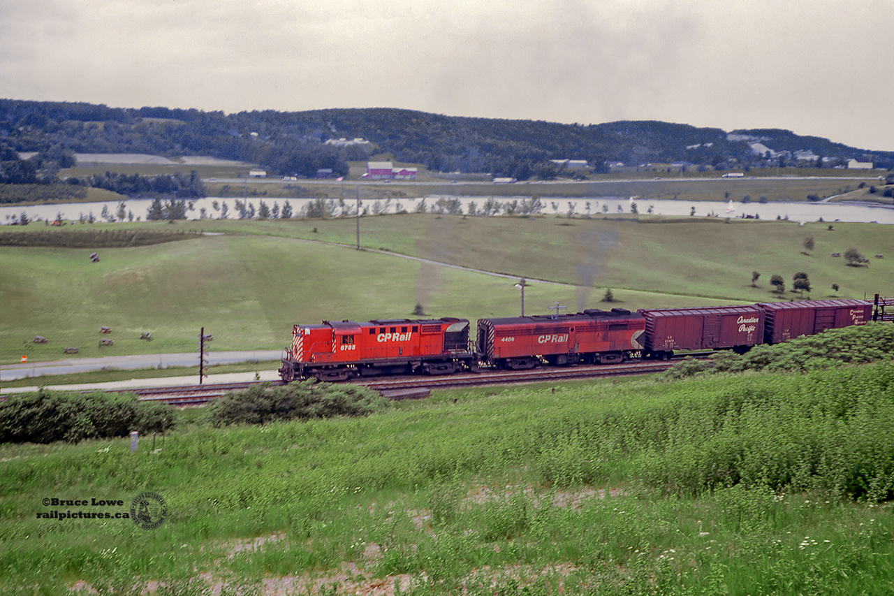 Rolling through Kelso Conservation Area, Extra 8785 west charges upgrade through Kelso with RS18 8785 and FPB-2 4466 up front.  Not much traffic can be seen passing Arawana Farms' barn on the 401 across Kelso Lake.  Built in 1958, 8785 would be rebuilt to CPR 1837 in 1987, and 1998 would be sold to the Minnesota Commercial Railroad as their number 83.  B-unit 4466, built 1953, is just a few years away from retirement in 1976.  It will meet the scrapper's torch shortly after.