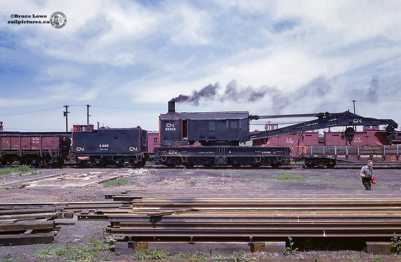 A summer day in 1965 finds CNR big hook 50008 all steamed up, likely for Belleville Railway days which occuredlate June/early July.  50008 is a Bucyrus Erie, 250 ton crane, built 1946 with serial number 36210.  Supplying the coal is tender 51585, and out front is boom tender 60033.  According to Bruce's notes this was the last steam big hook on the CNR roster, and would be converted to diesel in the near future.  Note two plows; CNR 55369, CNR 55396, and at least 3 flangerss visible in the yard.  Thanks to Paul O'Shell for information on this crane, as well as MOW equipment in the rest of Bruce's collection.