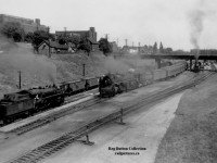 A busy scene at Hamilton's <a href=http://www.railpictures.ca/?attachment_id=38517>James Street North Station</a> as CNR U-2-h 6263; the second last 4-8-4 Confederation type constructed for the CNR by MLW in 1944, hauls a good size passenger train westbound under MacNab Street North.  At left a freight passes eastbound, while at right in the station a CNR U-1-f "Bullet Nosed Betty" (CNR 6060-6079; MLW, 1944) sits waiting to depart.<br><br>Opening in 1931, the James Street North Station served as the third station on what once was "Hamilton's Railway."  <a href=http://www.trainweb.org/oldtimetrains/CNR/gwr/Hamiltom_yard.jpg>The original, built circa 1854</a> by the Great Western Railway (headquartered in Hamilton) served the railway until 1875, when the <a href=https://www.canada-rail.com/galleries/ontario/hamilton11.jpg>second station was built</a> to accommodate the growth of the railway.  GWR would only use the new station for 7 years however, as the GTR would take control of the company on August 12, 1882.  Ground was broken on James Street North by the Canadian National Railways in 1929 for the new station, which would serve the company as well as VIA Rail, GO Transit and Amtrak trains over the years before closing officially on February 26, 1993.  VIA and Amtrak had moved to the new Aldershot station effective May 25, 1992, leaving only GO Transit serving the station until moving to the TH&B Hunter Street Station in early 1993.  In 2000, LIUNA; the Laborers' International Union of North America, would reopen the station as the <a href=https://dynamicmedia.zuza.com/zz/m/original_/6/e/6e35bbfd-0c3e-4b7b-8c23-5fbbfc11cad8/B822618989Z.1_20160920180618_000_GAD1NA3O7.2_Gallery.jpg>LIUNA Station Banquet Hall.</a>  In recent years this area has seen passenger trains stopping again with the opening of GO Transit's <a href=http://www.railpictures.ca/?attachment_id=20100>West Harbour GO Station</a> in 2015.<br><br>*Note the dual gauge tracks in the 'original' GWR station photo.  Beginning in 1870, GWR began rebuilding their line from Provincial gauge (5' - 6") to standard gauge for increased traffic from American rails.<br><br>More James Street North Station:<br>GO Transit in 1991 by <a href=http://www.railpictures.ca/?attachment_id=6617>John Eull.</a><br>Amtrak's "<i>The Maple Leaf</i>" in 1992 by <a href=http://www.railpictures.ca/?attachment_id=36825>Bill MacArthur.</a><br>A CNR 6167 excursion in 1963 by <a href=http://www.railpictures.ca/?attachment_id=39091>Harold E. Brouse.</a><br>
Eastbound Amtrak in 1986 by <a href=http://www.railpictures.ca/?attachment_id=4846>John Eull.</a><br>RARE COLOUR PHOTO; General Motor's "<i>Train of Tomorrow</i>" or Aerotrain in 1957 by <a href=http://www.railpictures.ca/?attachment_id=28477>Doug Page.</a>