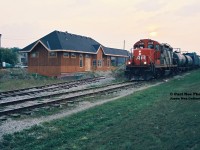 The 15:30 Kitchener Job is returning through Uptown Waterloo from Elmira with GP9RM 4138 during a hazy late summer evening. Normally, photography from this angle was not feasible due to the evening sun, however thanks to the haze a view of the train passing the new Waterloo train station, which was under construction at the time, was made possible. 
<br>
A year later in 1997, the station would be completed and become the new home of the Waterloo-St. Jacobs Railway (WSJR), which was formed by a group of local investors. However, eventually the City of Waterloo acquired the station in 2000 after WSJR had ceased operations due to operating costs. 
