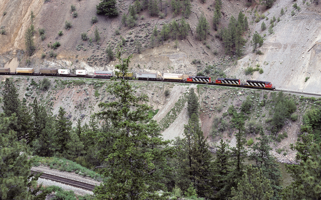 Photo of a CN express train in the Thompson river canyon about 7km north of Lytton BC. A small piece of the river can be seen in the lower right and the CP tracks in the lower left. The 5348 is being helped by the 5180 and 5079. Picture taken at the end of June.