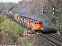 There was a time when blue and red Grand Truck Western power was common on CN freights in Southern Ontario in the 90's. Here, CN GP40-2L(W) 9410 leads #382 off the hill at Bayview Junction, leading GTW GP40-2 6417, GTW GP38 6206, CN SD40-2W 5336, and GTW GP38 6204. No dynamic brakes on the leader or most of the power, hence the cloud of smoke kicking up from the brake shoes. A few railfans are visible in the distance, catching some of the action at the bottom of the hill.
<br><br>
<i>Bill McArthur photo, Dan Dell'Unto collection slide.</i>