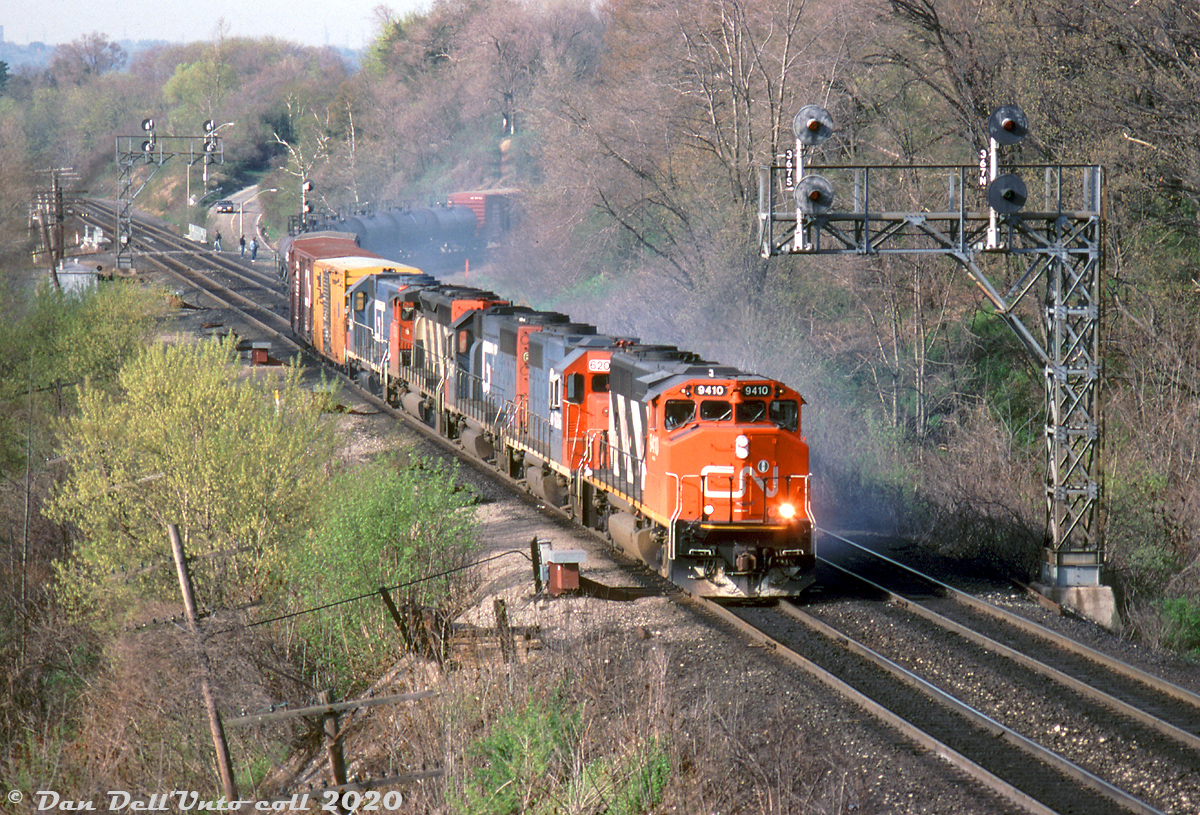 There was a time when blue and red Grand Truck Western power was common on CN freights in Southern Ontario in the 90's. Here, CN GP40-2L(W) 9410 leads #382 off the hill at Bayview Junction, leading GTW GP40-2 6417, GTW GP38 6206, CN SD40-2W 5336, and GTW GP38 6204. No dynamic brakes on the leader or most of the power, hence the cloud of smoke kicking up from the brake shoes. A few railfans are visible in the distance, catching some of the action at the bottom of the hill.

Bill McArthur photo, Dan Dell'Unto collection slide.
