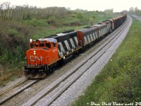 CN only rebuilt 10 of its GMD F7B freight B-units as part of their F7Au/F7Bu rebuild program in the mid-70's, but they got their mileage out of the cabless units and seemed to use them wherever they could, whether it was in pure A-B-A Sets of F-units or mixed in with other models at random.
<br><br>
Here on a less-than-ideal day, Reg was out to capture a rather unconventional lashup: CN GP40-2W's 9640 and 9656 splice F7Bu's 9198 and 9196, flying white extra flags on train #431 (with pulpwood racks up front) as they roll into Niagara Falls at Portage Road. The purists would scoff, but I suppose this qualifies as an "A-B-B-A" consist. The figures on the hill in the background are golfers enjoying some time on the course nearby.
<br><br>
<i>Reg Button photo, Dan Dell'Unto collection slide (with some editing and cleanup)</i>