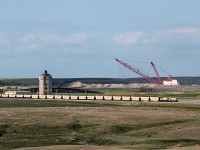 Prairie Coal, on contract to Sask. Power, hauls coal 5 miles south from the mine to the Poplar River power plant. A loaded train departs the the loadout with an SW1200 and modified SW for US army.