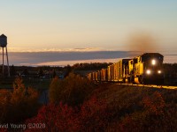 The forestry crisis had left its mark in northern Ontario by 2010 and the crew of Ontario Northland train 213/ 414 are only venturing north to Cochrane twice a week. It makes for a long day of building their train in Englehart, performing any work online plus a side trip into Iroquois Falls before yarding at Cochrane and turning back to Englehart. <br> At the end of a gorgeous fall day, we catch up to southbound 414 accelerating a large freight over the bridge at Monteith and past the towns signature water tower and correctional facility. The crew will get into Englehart a couple hours later before resting quickly before having to be on duty to switch the yard first thing thing in the morning.