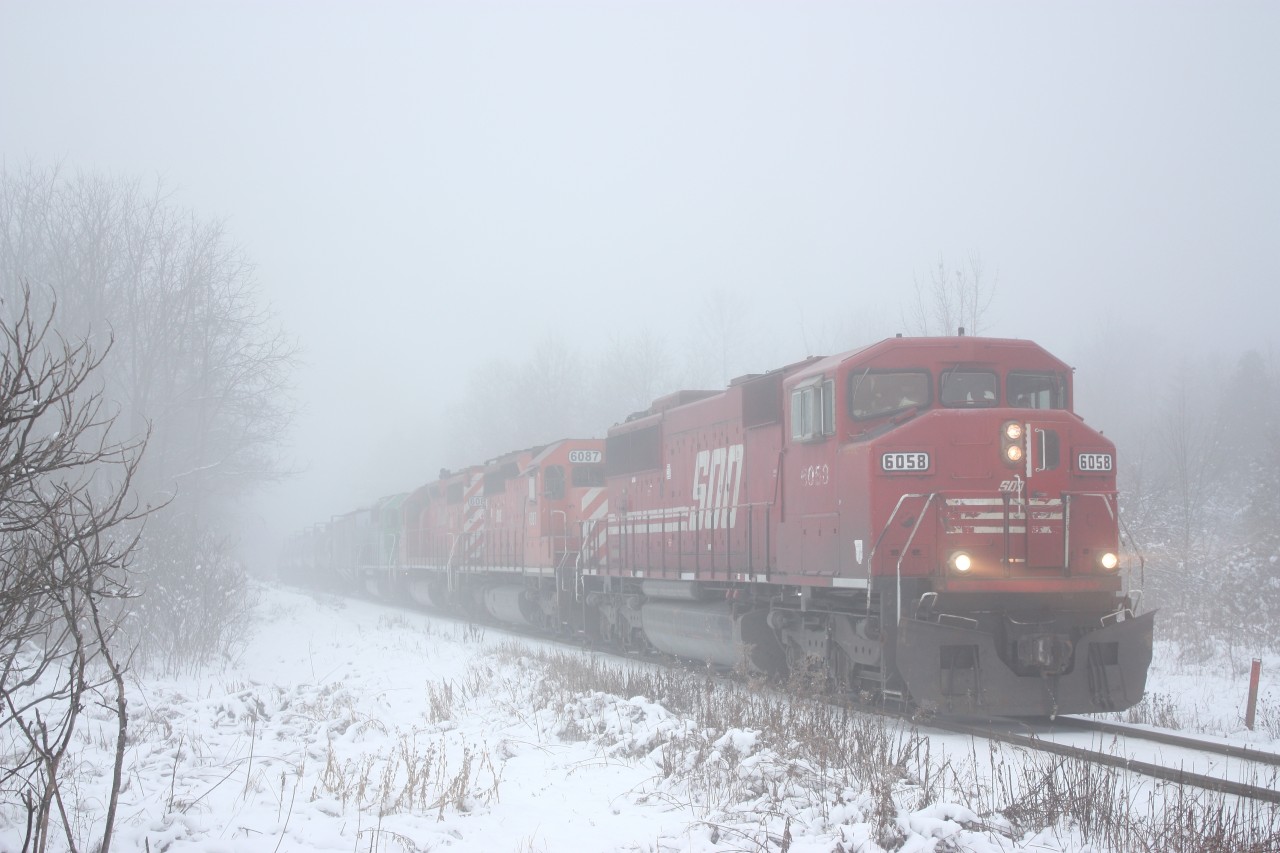 The headlights of SOO Line SD60M 6058 pierce through the thick fog as it leads a southbound tank train just south of Guelph Junction. The trailing SD40's were sold to the DME years earlier even though they still carry CP action red. A leased GCFX SD40 is fourth in the consist. Their was a time when unit tanker trains were common on the Hamiton subdivision, but those days are long gone now.