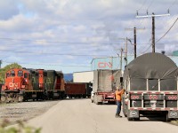 Hamilton has always built itself around the steel industry, in all of its forms, from raw steel coils, to new freight cars,as well as scrap metal and everything in-between. The full cycle can be found all around Hamilton. At Parkdale CN's International Bulk services building is used to offload everything from coils to large spools of wire while right next door a large scrap metal recycling facility loads gondolas. Here we see a truck driver unlatching his tie downs on his trailer as he waits for CN's local to clear the path to the CN transfer building. The crew of the train are busy collection gondolas full of scrap metal next door. 