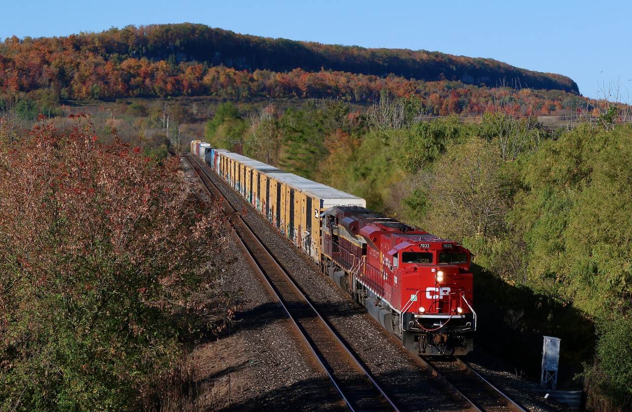 The Niagara Escarpment in the background is a blaze with fall colours, while turkey vultures soar high above, as CP train 234 coasts down the Escarpment with dynamic brakes engaged on both SD70ACU's (former SD90"s). The train is just entering the town of Milton as it continues its journey east to Toronto on this cloudless autumn day.