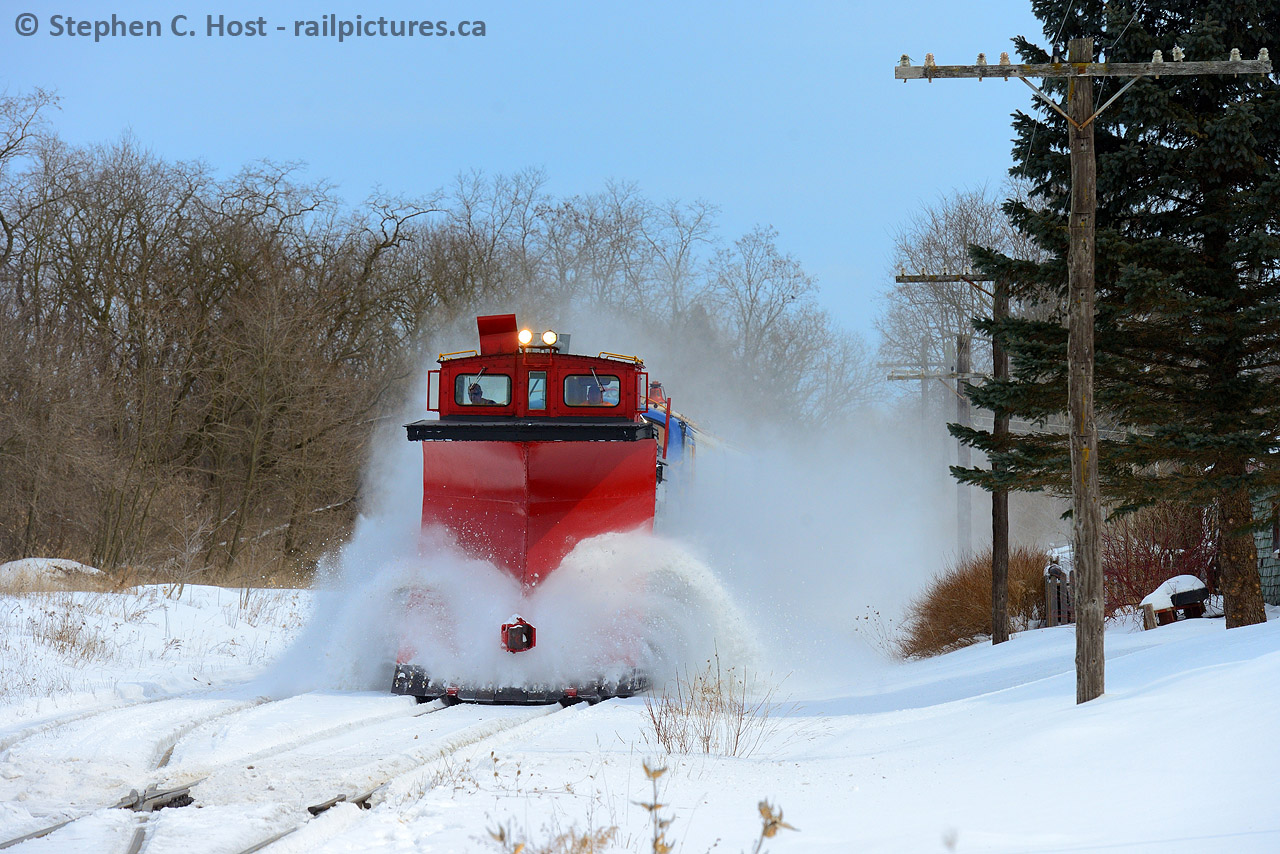 OSR's early March 2015 plow extra is westward on the St. Thomas sub in Beachville flanging the right of way before the next deep freeze. Foreman Jack Hyde who is operating the plow lifts the blades for the west switch Beachville, because if not those blades will hit the rail (ouch!). You can see the flow of snow has momentarily stopped onto the plow. Once they clear the crossing in downtown Beachville they'll lower the blades again. Notice how this late in winter so much snow has fallen it rests above the railhead no matter where you are? That's why they flanged, essentially digs a few inches below the railhead and clears the snow from either side of the rails. If it warms up and freezes it becomes ice and can cause lots of trouble, so they take no chances and flange just in case. Winter 2015 was notoriously bad, OSR must have ran two dozen plows that year, but in 2 weeks you'd hardly know there was any snow here..