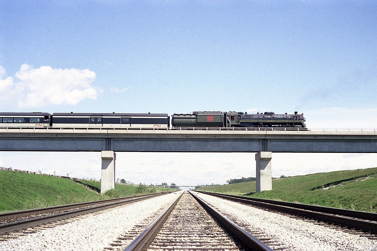 Looking eastward down at Townline Tunnel track level at CN 6060 reversing for a run-by. On Wednesdays I would catch the twice weekly (in the summer) steam excursion out of Toronto doing the 'side trip' from Niagara Falls station, down the Stamford and running the wye at Yager. Passengers detrained just to the south of the tunnel tracks, the train reversed (as seen) and then were treated to an enthusiastic and smoky run-by. The train then backed around the wye and took the riders back to Niagara Falls.  Nice side trip. Only cost about $10 at the time.
The townline tunnel track (new CN Cayuga) I am standing on was removed in the 1990s. Currently there is only the CP Hamilton sub and the Brookfield siding remaining.