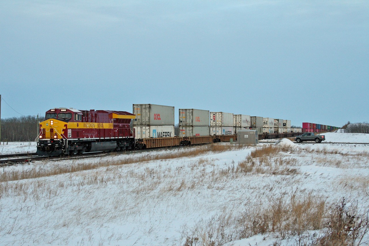 CN 3069, sporting Wisconsin Central colours, leads Chicago to Vancouver train Q 11791 21 through Chauvin, Alberta in the last light of a busy day on the Wainwright Sub.