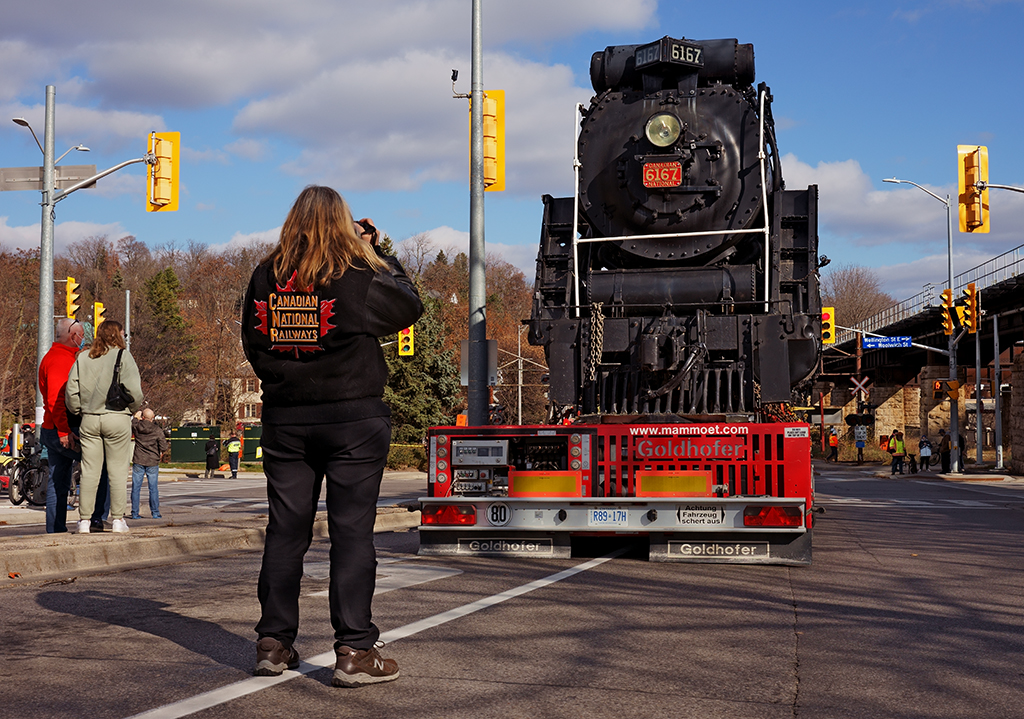 Nice Jacket! Many onlookers came to observe the movement of CN 6167 from her current location on the south side of the Guelph Sub to her new home at John Galt Park just down the street. Many took photos such as this one, others took video of the special move, so here CN 6167 sits waiting for her turn to be moved to her new spot on this warm sunny morning.