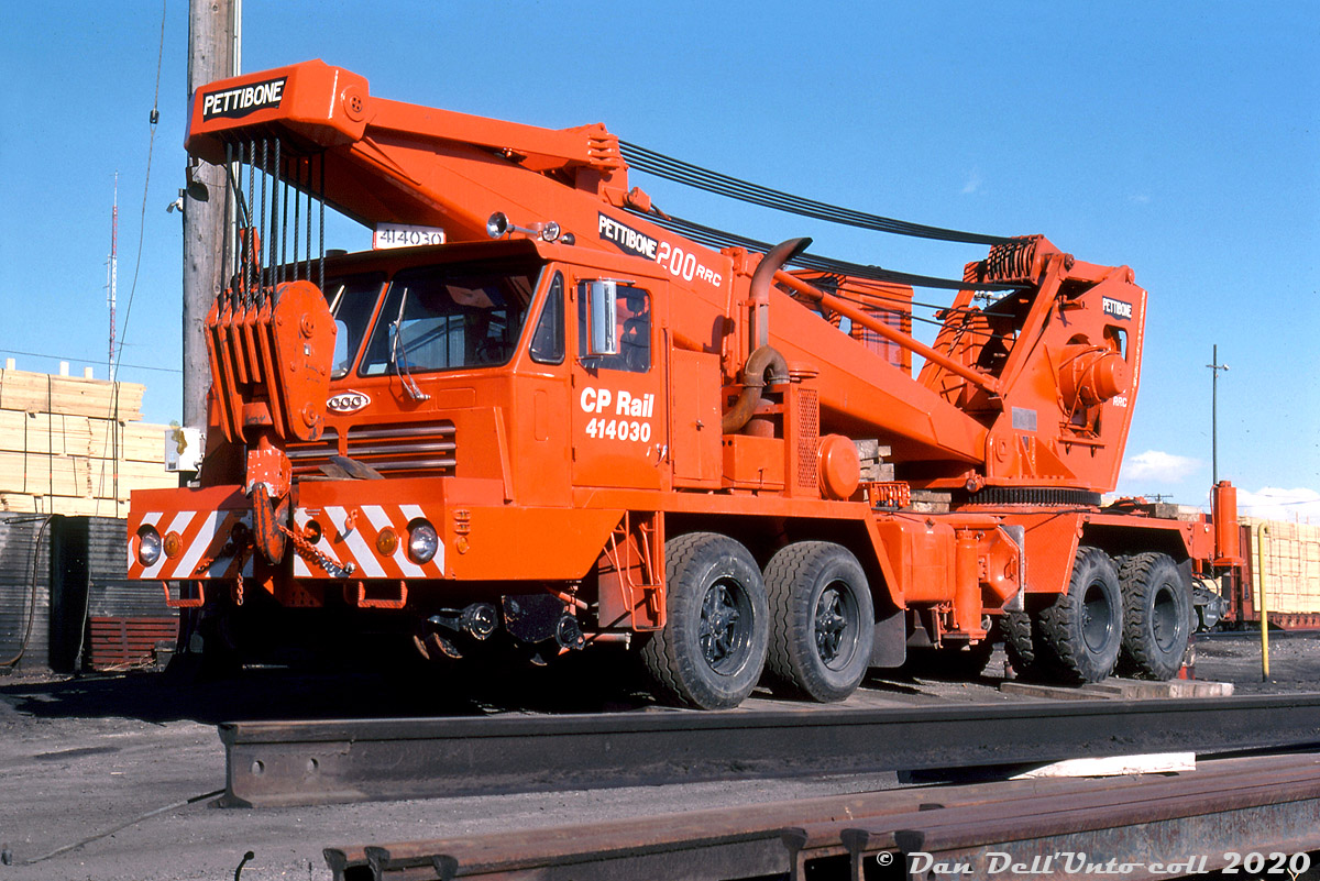 CP 414030, a nearly new 100-ton Pettibone 200RRC hi-rail truck crane (built 1976) is seen sitting in the sun at Calgary awaiting its next call to duty. Pettibone is a material handling equipment company (manufacturer of cranes, Speed Swings, telehandler forklifts, etc), and the CCC on the cab is for Crane Carrier Company, a manufacturer of heavy-duty and vocational truck chassis. The CP-style numberboard mounted on the cab roof is a nice touch.

Despite its shiny appearance, the wear on the hook suggests it's seen some service already. These kinds of cranes, more versatile than older rail-mounted cranes (they could be driven over the road to minor derailments, rather than requiring a train to be ordered to transport them there), were often used inside yards and out on the road for various tasks including wreck cleanup, rerailing derailed cars, and changing out trucks and traction motors. The first ones started showing up on CP's roster in the early 1970's, and eventually they had about a dozen or so stationed at various yards and terminals across the system, all numbered in the 4140xx series including units built by Holmes and Pettibone.

Photographer unknown, Dan Dell'Unto collection slide.