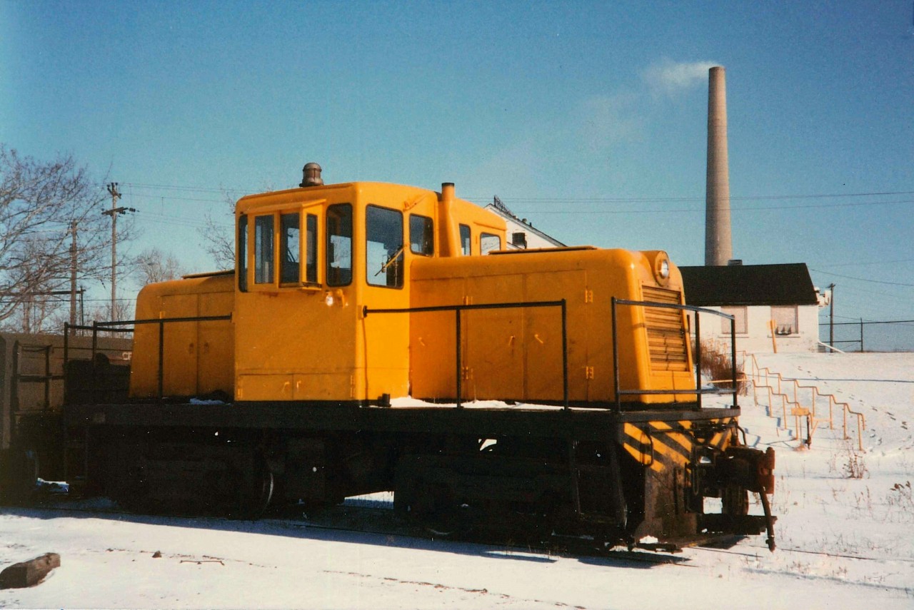 Unnumbered GE Center Cab (likely #4) is back on switching duty shuttling around gondolas of pig iron on the property of the Canadian Furnace Division of the Algoma Steel Corporation.  In the background is the 750' tall INCO (International Nickel) stack in an active role until Electrolytic Nickel production ceased a few years after this photo was taken.  The stack was removed by the mid 90's.  The white brick building in behind was originally the Cronmiller & White Brewery, constructed in 1855 by Jacob North, producing the iconic "Maple Leaf" Beer.  The building still stands today.  The locomotive was on the property from 1949 (new) till 1981, and is now part of the Colorado Railway Museum, Golden Colorado (repainted in black and numbered as - #4), courtesy Paul O'Shell - #4 information.