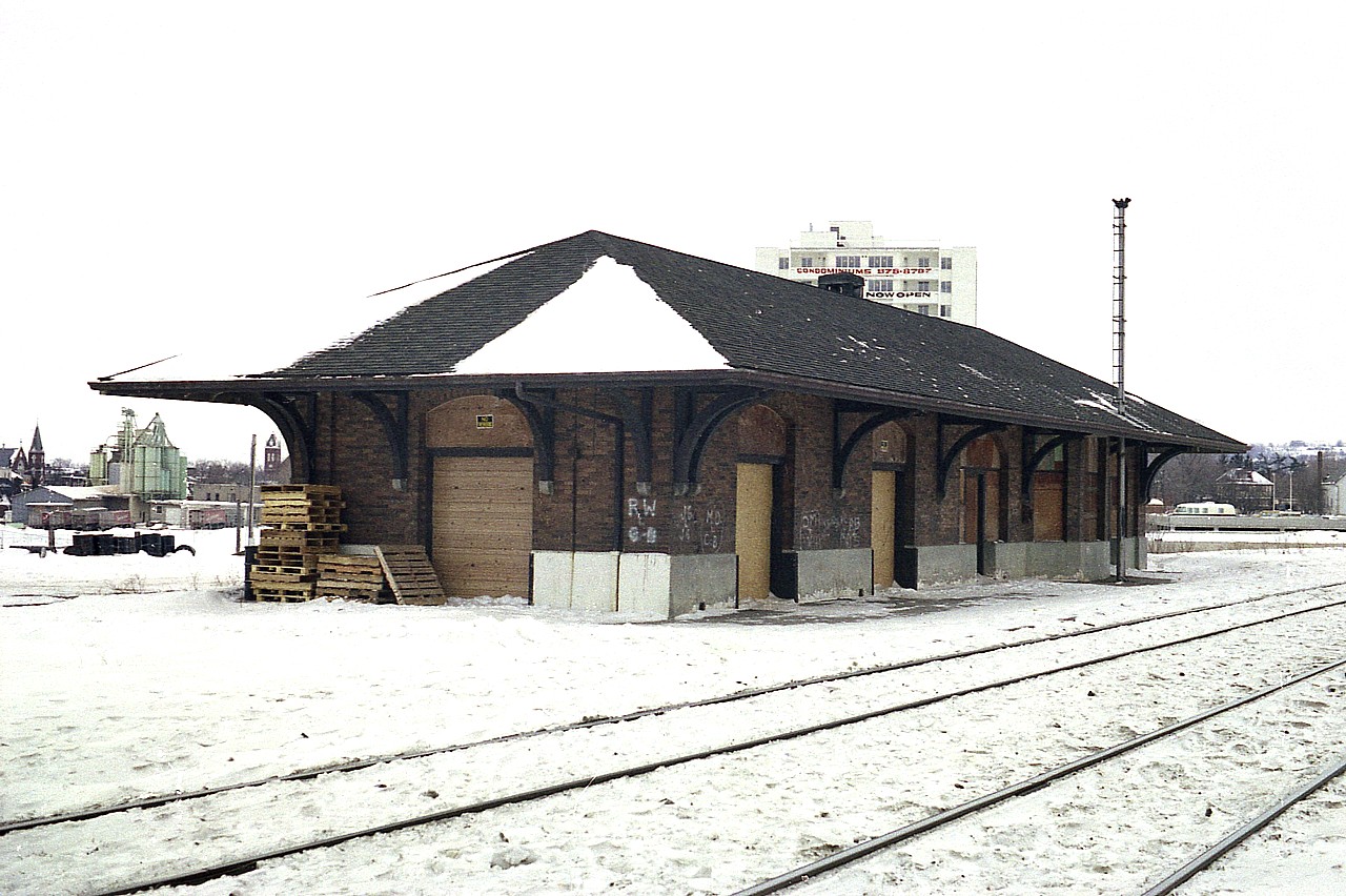 Not many of you will remember this station.  No wonder. It was torn down not long after I grabbed this shot in early 1977. I haven't the date handy, but it was gone by the end of the year. Those familiar with Milton can see
this was but a small town in 1977, and the condo building behind it might have been one of the very first of many that has turned the place into the city that it now is.
The station was at the end of Court St North, on the south side of the tracks. Built around 1910. Passenger service ended in 1968 and from then on in, I guess it awaited the wrecker's ball.
Pity the namesign is gone,(no I don't have it) as the one on the other end was still intact.