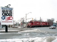 Back in the day, not all that long ago.  The Canadian and American dollar were almost at par; the locals were streaming to the USA to take advantage of the fact and get their "cheap" groceries & gas.  A billboard campaign to try and slow the tide (seen on the left) really had little effect. Back in the day GP9 locos seemed to be everywhere on the system, and better, there were lots of trains and rail traffic in Niagara Falls. Not any more. The CN yard is desolate, the CP Montrose yard is gone; the CP main thru the city is gone as well as this connector and to see anything in trains at all, one has to wander down to Fort Erie in hopes something is rolling by the defunct CN yard down that way. How times change!!  The image here is CP 8227 and 8246 heading back to Montrose from the CN yard, crossing thru the intersection of Victoria and Bridge Sts.    Nostalgic.
