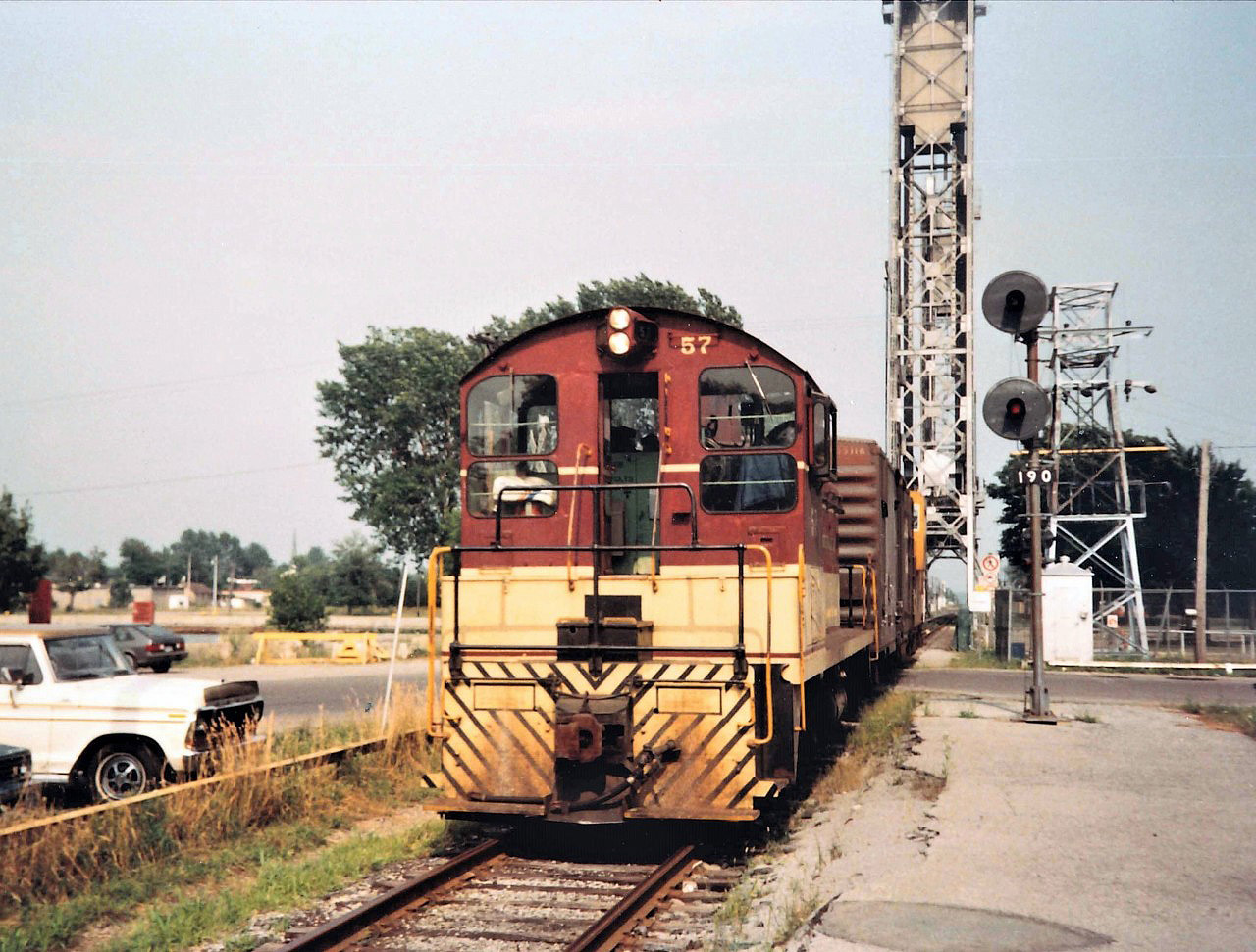 TH&B #57 has just crossed the Welland Canal Lift Bridge #20 with a single box car and Van #83 in tow bound for the Maple Leaf Mill.  The Bridges were staffed 24/7 for the 9 1/2 month shipping season.  Bridge 20 was removed less than 10 years after this photo was taken.  My trusty 1986 Vette (Chevette)is seen in the background.