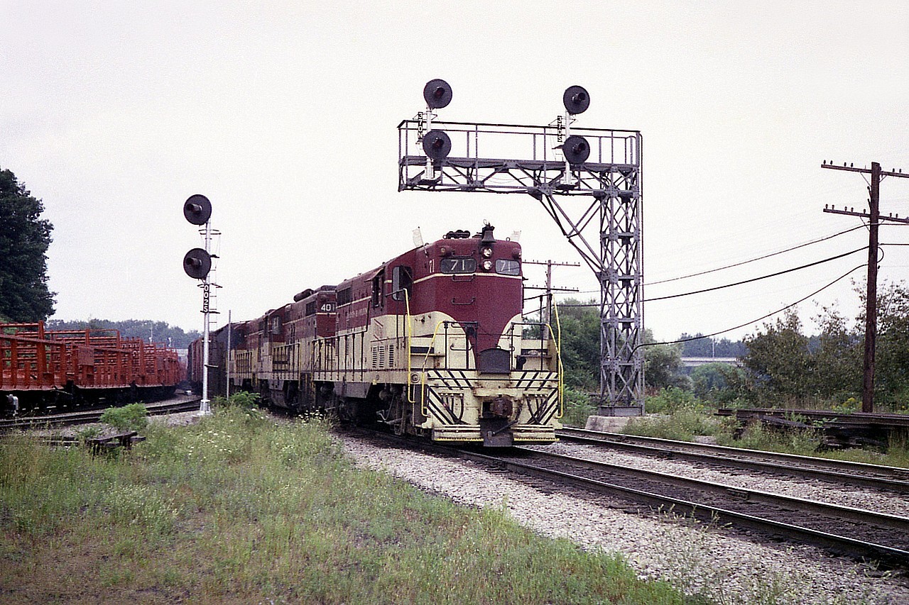 The long days of August helped make the Starlite a decent shot back in the day; as the train often did not
roll thru until the dinner hour or later.  Here we see all-TH&B, 71, 401 and 77 Hamilton bound, passing a rail train on the line heading up the Dundas sub.
Twenty seven years earlier, in Aug 1950; the TH&B 71 was the very first locomotive ever constructed at the GMD plant in London, Ont. And two and a half years after this picture was taken, the GP7 would meet its demise in a violent truck-train collision in Pelham.