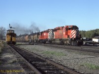  For my 100th RP.ca image and the last for 2020 lets go back to Aug 19th 1984. I'm working as a CP Operator at the temporary train order station Kaministiquia.  The wood caboose CP437188 is not just my office, but my accommodation. 
 I worked here for about six weeks on loan from the London Division.  The trainorder signal on the roof was operated using two chains and a hook inside the van. Westbounds would get orders here as they had the track gangs out working between Kam and Raith and would crossover here. The double track main was also left hand running which took some getting used to. A lunchbox radio was used to contact the Winnipeg Dispatcher. Once a train was cleared it, the orders were clipped into a wood hoop. The trainorder signal only had two positions red/green so if orders were 19y (Yellow) you would place the signal red and use a yellow flag.  On the weekends they Operators were allowed to go to the hotel in Thunder Bay. If the van needed servicing (Stove oil, fresh water tank filled and crapper cleaned out) the signal had to be secured by climbling on the roof, pulling out a large cotter pin and lowering the whole signal and posts onto the roof and then strapping it down.  The first time I did this was at night in the rain. I didn't realize it weighed more than I did and it came crashing down and the light came off and went off the roof, luckily it held on by the electric wire and I did not fall off the roof. 
  The accomodations were pretty sparse.  Just a caboose mattress for bed (BYO Sleeping bag) and an oil stove (BYO food) and toilet. Luckily the gang cars got parked in the siding across the tracks and I was able to take advantage of the kitchen car and commandeer some hot meals. 
  Here we see an Extra East led by 5937-5924 and two B&O GP40's passing my office.  I was able to shoot this as they did not require orders.  On the right side you can see my 1976 Chrysler Cordoba that I purchased from Bruce Mercer while I was working in Chatham. That car got totalled a few days after returning to Windsor when I got hit by an impaired delivery truck driver. (No injuries)
 I also worked at Dyment and Hawk Lake on the Ignace Sub before returning home.  
 One funny story, the temporary trainorder station hours were listed on trainorder given out of Thunder Bay. I believe it was a stat holiday, maybe Labour Day and this Westbound comes flying around the corner (Usually they would slow right down) and I'm standing there, signal red waving the yellow flag in one hand and hoop in the other. Well the front door of the SD40 flies open and the headend trainman just makes it to the steps to snag the hoop which proceeds to whack him in the face. The train is now in full emergency braking and when stopped I see the headend trainman marching hastily towards my van with hoop in hand. "Oh S**t" I make a hasty retreat and lock the door thinking he was pissed at me. Turns out he was mad at the hogger who assumed the office would not be open on a stat. By this time the Conudctor has walked up from the van to see whats going on. After getting the brakeman cooled off they exchange positions with the conductor going to the head end and the trainman to the van with a nice welt on his chin.

Happy New Year