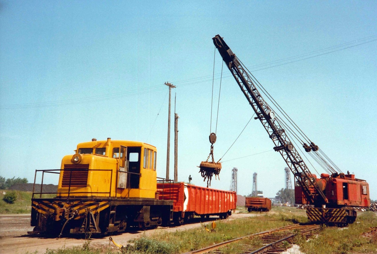All is good in the world, Gondolas of Victoria Pig iron are loaded by American Rail Crane (blt. 1957) and shuttled around by the unnumbered GE Center Cab (blt. 1949) at the Canadian Furnace Division of the Algoma Steel Corporation.  The Blast Furnace situated on the east bank of the Welland Canal had an extensive rail network to move around metallurgical coke and other raw materials used in the Iron Making process, slag pots for dumping molten slag, and gondolas for shipping out the finished product.  Welland Canal Lift Bridges #21 (autos/trucks) and #20 (rail - ex CNR Dunnville Sub) can be seen in the distance.  Given that the Gons are CPR, the shipments would have likely been picked by the TH&B which retained running rights into Port up to the end of 1988.  The scene looks very different today with all the rails gone, Bridge #20 gone since 1997, and much of the property used for raw material bulk storage (Salt, Sand, Calcium Sulphate-Gypsum, etc) offloaded by lake ships. As a side note, there is growing interest in Pig Iron to help offset the rising prices of Scrap used in EAF - Electric Arc Furnace steelmaking with STELCO Nanticoke commissioning their new Pig Casting machine in Q1 2021.