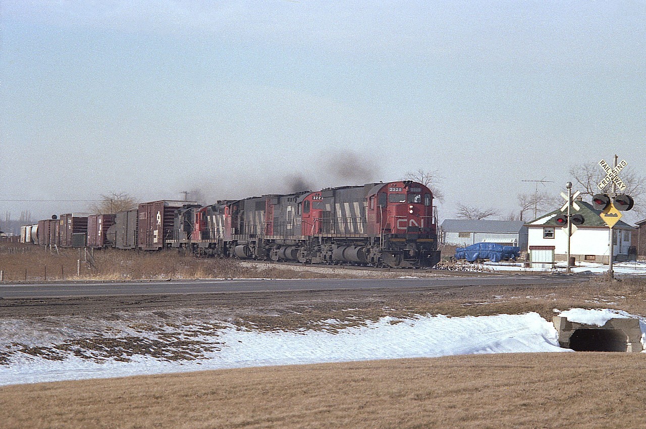 Interesting assortment of locomotives on this Toronto-bound train notching up as it hits Lundys Lane (Hwy 20) in the Falls after just leaving Port Robinson. There is CN 2328 (M-636), 3223 (C-424), 9635 (GP40-2L(W), and 4505 with 4580, a pair of GP9s. And no autos or truck traffic to spoil the photo.  This was shot with Fuji 100 ISO (or ASA, as referred to back then)film, using a Pentax K1000.  time is taking its' toll on these old negatives.