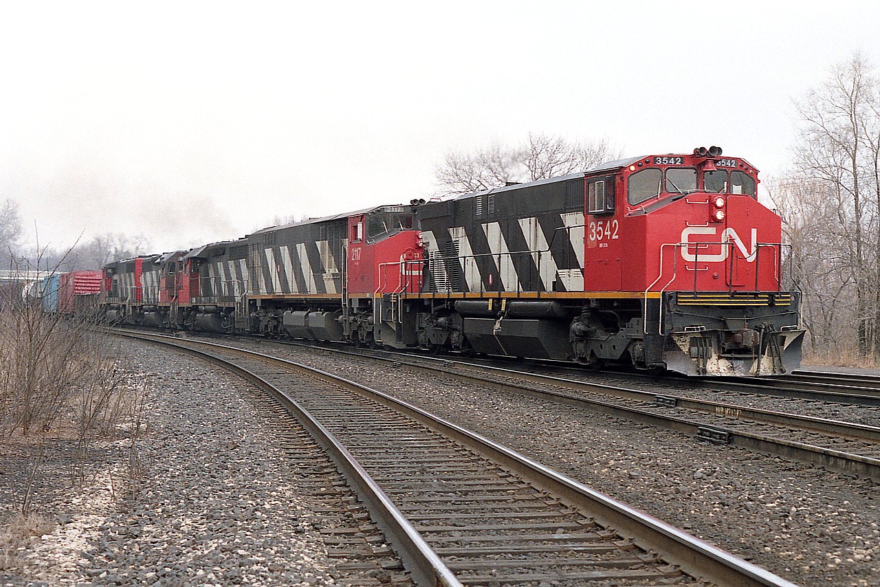 As most of you on this site are probably tired of hearing by now; locomotive variety was much more impressive in past years than it is today. There were periods in which anything seemed to show up. This image is not an extreme example, but it is interesting.
This is a Mac Yd to Fort Erie train:  CN 3542, 2117, 9307, 9316 and 9624 the power.
The 3542 was renumbered from 2542; sold to Hudsons Bay RR. The CN 2117, BBD HR616 was one of 20 behemoths from Bombardier, so unreliable they were all pulled from the roster by 1998; and this unit was peddled off to NRE.
The 9307 and 9316, GP40s, one went to RMGX and the second to Roberval & Saguenay as their #65. And the trailing unit, 9624, a GP40-2 (W)?  Well, it got itself retired in 2001.