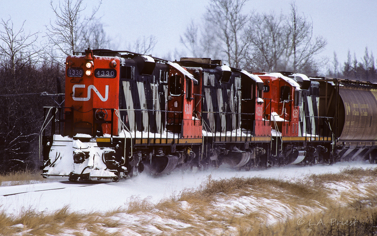 Grain loads heading back to Edmonton on a cloudy Saturday morning. The 4330, 4350 and 4351 have 40 grain hoppers cruising at track speed as they come around the corner which will lead to the bustling hamlet of Coronado. The 3 units are numbered very close together, yet, only the one has spark arrestors. It seems having them is at the discretion of the fellow putting them back on after maintenance.