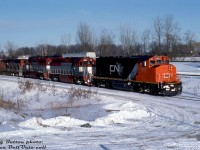 CN GP40-2W 9657 (in the snappy CN North America livery) leads EMDX GP40-3's 200 & 201 and a ratty zebra striped CN 9653 on train #333, seen at Aldershot on a cold February day in 1994. The two EMD lease units are former GO Transit GP40-2 units 725 and 726, and have recently joined the EMD lease fleet (they were originally built as GP40's (non-Dash 2) for the Rock Island, before becoming GO commuter units via Chrome Crankshaft after "The Rock" went bankrupt).<br><br>As more F59's joined the roster in the late 80's and early 90's, GO's older "40-series" units were either sold off or leased out. Eventually GO 720-726, after doing time leased out to CN and CP (at least two even made it out to Alberta), were used as trade-in credit to EMD for GO's final order of F59PH's (562-568) built in early 1994. EMD didn't waste time repainting the Geeps in their maroon, silver and grey paint livery, renumbering them into the 200-series, re-equipping them with dynamic brakes, and leasing them out in freight service.<br><br><i>Reg Button photo, Dan Dell'Unto collection slide.</i>