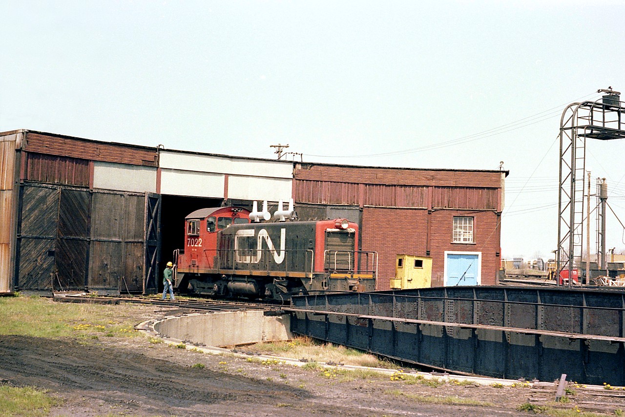This rather idyllic scene appears to have 'old time' all over it. At least for me. It is a nice quiet warm Sunday morning in early May, and things are peaceful  at the Fort Erie CN facility. I just happened around the back to see CN 7022 about to be turned and came up with this image. Cannot recall whether the loco had just emerged from the roundhouse but it appears so.  Most of us took these scenes for granted, until it happened that the all of a sudden we noticed; hey, the turntables and roundhouses (as well as MoW sheds, trackside phones) and all the rest of it have disappeared along with the personal side of railroading.
I cannot remember when the r'house and table were closed down. Probably early '80s.