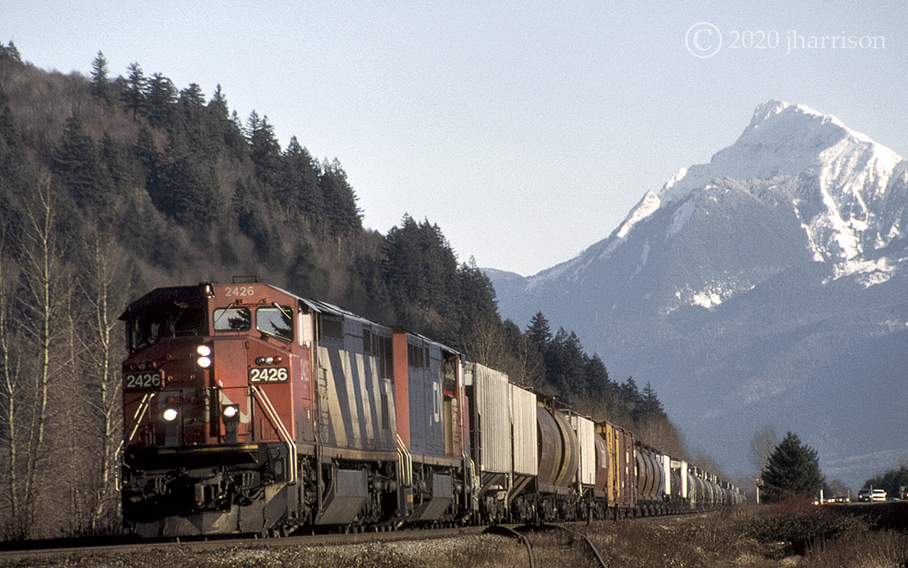 With 7000 foot Mt Cheam towering in the background, CN 2426 and 2442 have just left Chilliwack as they head west at Arnold on CNs Yale sub. On a clear night, the lights of Vancouver Island can be seen from the peak of Mt Cheam, about 180 Km., Chilliwack to Nanaimo.