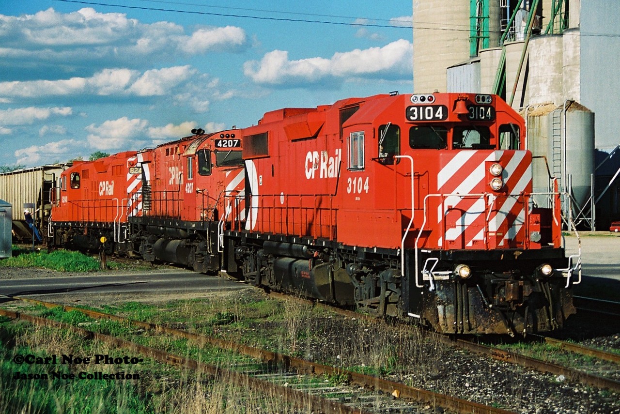 On a warm spring evening, the CP Hamilton Turn (525) is viewed lifting a cut of 12 hoppers at Ayr, Ontario on the Galt Subdivision. Powering the job are 3104, 4207 and 8240, which will soon depart westbound to London with 26 cars and for a meet with 516 at Blandford. My notes showed 516 later passing through Ayr with 5565, HLCX 6203, 4248, 5643, GATX 903 and 5612.