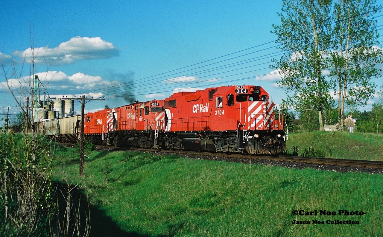 On a pleasent spring evening the CP Hamilton Turn (525) is pictured departing Ayr, Ontario on the Galt Subdivision after lifting 12 hoppers with 3104, 4207 and 8240. The train is approaching the Nith River bridge with 26 cars and is heading west with an eventual meet with 516 at Blandford.