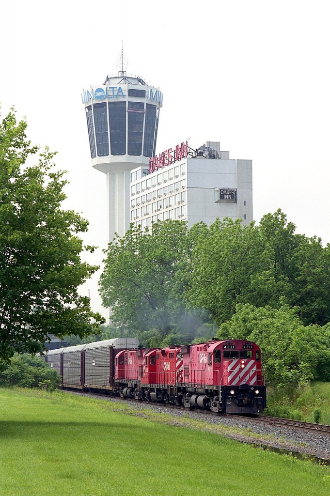 About 6 years before all the track in downtown Niagara Falls was torn up for a Casino and other atrocities, we see CP 4211 leading 8248 and 4233 past the Minolta Tower on its way to the USA.  This is June, the weather is great, and the real fun begins when everyone starts cursing and bitching when the train fouls the Clifton Hill tourist area. I was probably the only one who enjoyed it. Never-the-less, no matter what it was like, traffic was so bad in the falls during tourist season (almost all year) that it wasn't worth the effort to try and get ahead of this train and catch it again before it made the bridge. All three locomotives on this train are now off the roster; and the two MLWs have gone to where sometimes I wish I could. The Apache Railroad in sunny Arizona!!
It would be interesting to revisit this spot and check the view today. It is now so full of hotels it would look more like downtown Toronto than little ol' Niagara.