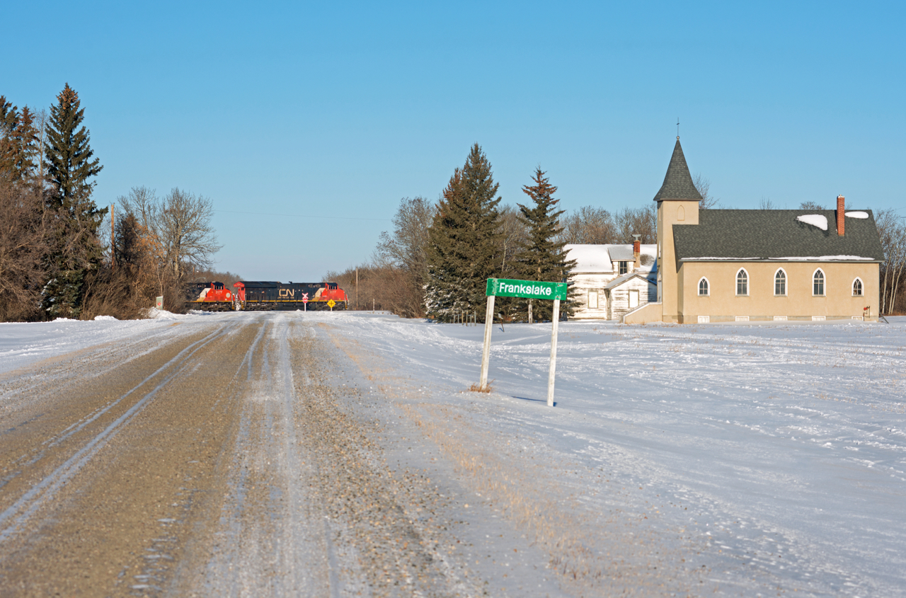 CN's Regina to Melville train 423 is seen passing through Frankslake Saskatchewan. The church at right was moved to it's current location in 1937, some 26 years after the railway arrived in 1911.