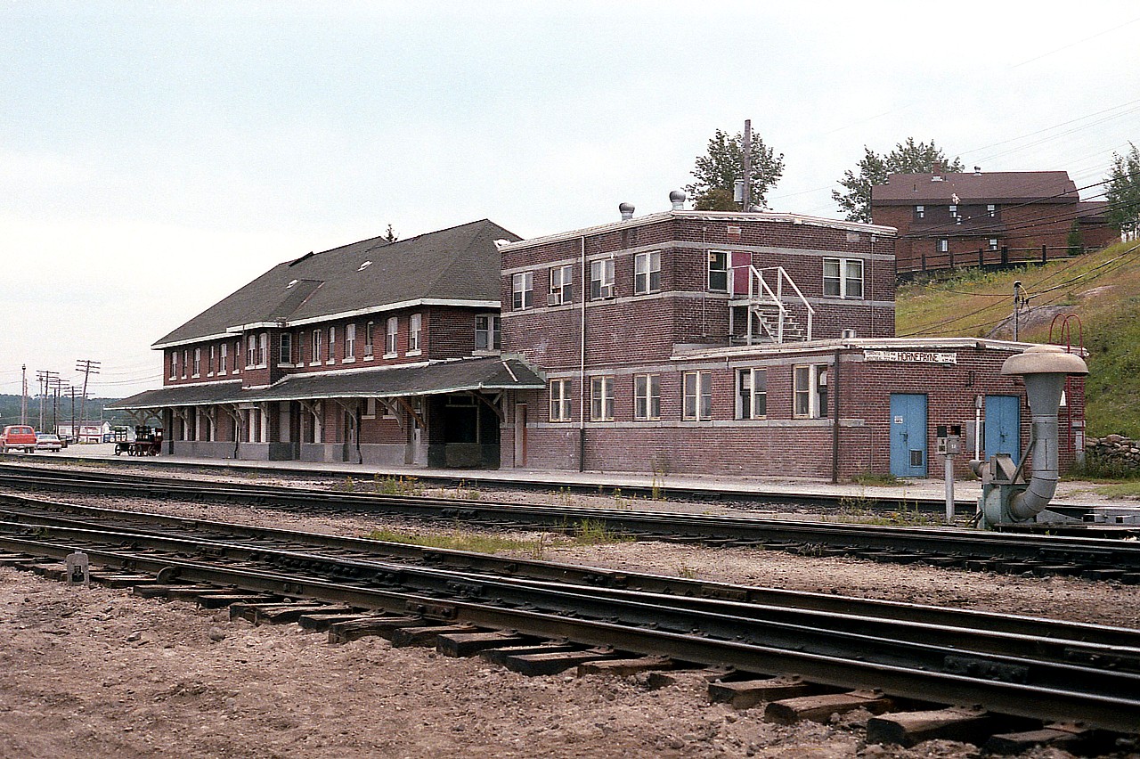 Stations didn't get much larger than this in the North. This rather isolated and barren community was once a vital link in the CN system. It featured a huge yard, an enclosed roundhouse !!!   and other advanced features to protect employees from the elements, as winters could get rather severe. However, times have changed. The community is no longer what it once was, CN has eliminated most of the facility over the years, and the need for this huge station with it's adjacent telecommunications centre is no longer.
The station itself was built back in the 1920s, the modern looking brick addition in the 1950s. It housed train dispatching offices on the upper floor and CN telecommunications (new centralized signal system)  on the lower. A small addition housed battery rooms and a standby generator. Access between buildings was gained by an upper level walkbridge.
Hornepayne is dying. The major structure than housed commercial tenants in town, the "Hallmark" building, went broke in 2011. CN downsizing has people leaving, looking for work elsewhere. Population of 1600 in the 90s is now below 1000. The demolition of this huge station complex, a shadow of once was, is just another kick in the teeth, even though it had far outlived it's usefulness and was more of a fire trap than anything else.
Looking back, I cannot help but wonder what became of the gorgeous station sign that once adorned the front entrance, and the plight of the probably 500 pigeons that called the old structure "home".