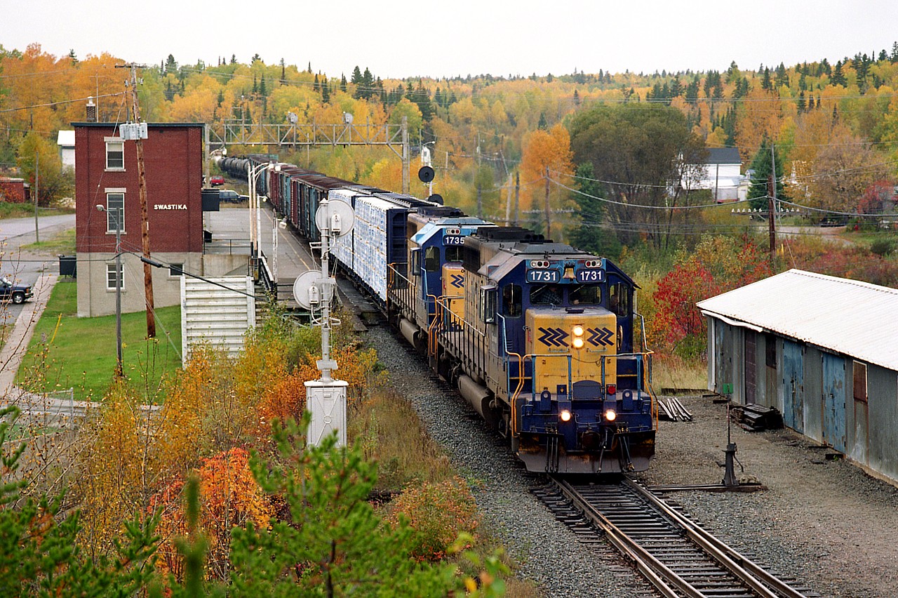 Fall colours in full swing at the end of September in Northern Ontario. It is a beautiful scene as ONR 1731 and 1735 power a train southward on their way from Cochrane to Englehart.
The 1735 is still rolling over the ONR, but 1731 was sold in 2005. Speeder houses and other various outbuildings on the bottom right of the photo have all been removed.