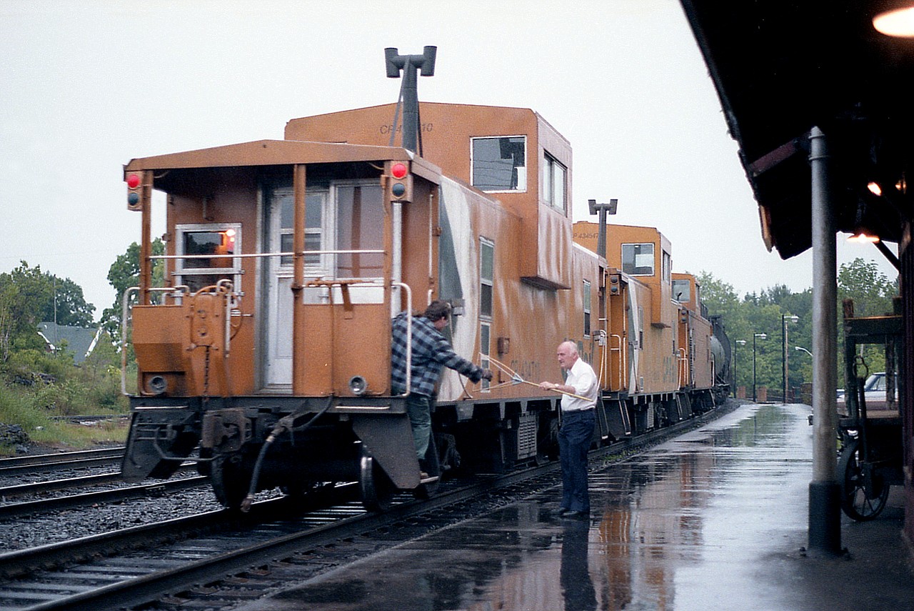 How it was done. "Custodian" Jimmy Bell hands up the orders to southbound CP 4509,4218's tail end on a warm but rainy Wednesday in June 1986. Every time I visited him at the CP station in town it was like being welcomed back home. Jimmy is gone now, but to this day he remains the nicest agent I even had the pleasure of chatting out an afternoon with. He had quite a bit of memorabilia out at his cottage on Georgian Bay; and when I expressed great interest in it; he got a ladder, went out, and tore the namesign off the north end of the station and told me to take it home as a souvenir of our good times. Needless to say I still have it.