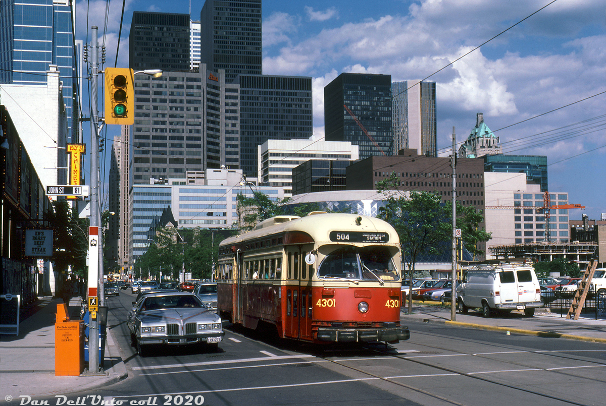 A fairly modern 1980's view of the downtown Toronto skyline shows a nice variety of architectural styles in this selection of skyscrapers (before the present-day glass-clad everything style took over). TTC PCC 4301 (an A13 class streetcar built new for Toronto in 1947) operates on the 504 King Street route, stopped westbound at John Street. In their final years in service, much of the TTC PCC fleet suffered through the indignity of large font numerals slapped over the original (smaller) painted out numbers. The water bumpers, while a neat concept, were also somewhat unsightly.

By this point in time, the old CP/Dominion Express freight sheds that used to be in the King/Simcoe area had been knocked down a number of years prior and replaced with the new Roy Thomson Hall, while the rest of the property remained parking lots until eventual redevelopment into Metro Hall. "Honest Ed" Mirvish, best known for his Bathurst & Bloor discount store, also owned a line of storefronts on this stretch of King Street including the Royal Alexandra Theatre, Ed's Warehouse (restaurant - roast beef and steak), Ed's Chinese, and Old Eds (although most closed over time).

Glenn Smith photo, Dan Dell'Unto collection slide.